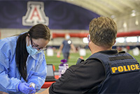 Phlebotomist Krystal Wiley, with the All of Us Arizona Research Program, draws blood from a University of Arizona Police Department officer for antibody testing related to the COVID-19 pandemic. (Photo: University of Arizona Health Sciences/Kris Hanning)