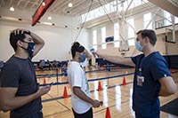 University of Arizona student Heath Zuniga (left) watches as Wyatt Snell, a clinical research coordinator, takes student Mason Young's temperature prior to the self-administered COVID-19 nasal swab testing procedure. All students living on campus were required to test negative before moving into their dorms. Students who live off campus were also offered free tests. (Photo: Noelle Haro-Gomez/University of Arizona Health Sciences)