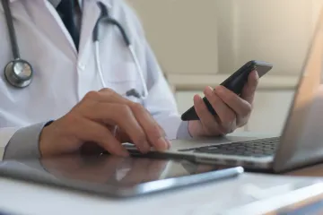 Doctor using a laptop and smart phone.